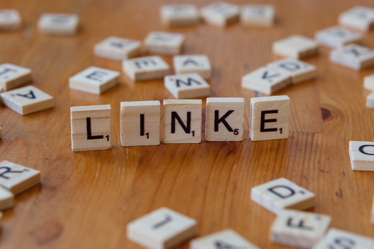 Scrabble tiles arranged to spell LINKE on a wooden table, surrounded by scattered letters.